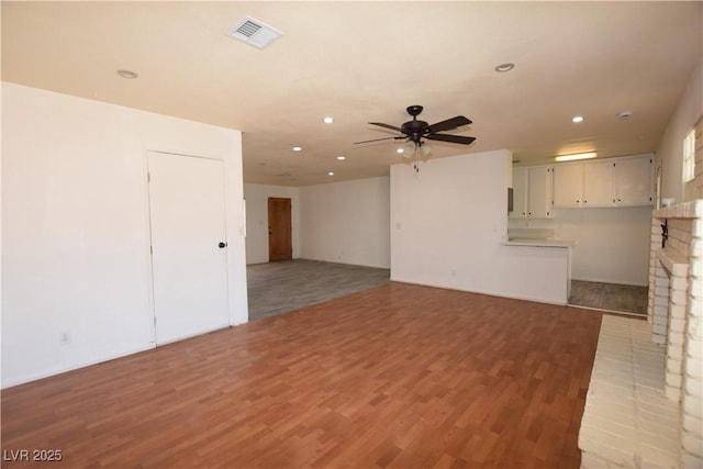 3323 Bancroft Cir, Las Vegas, NV 89121 - unfurnished living room with light wood finished floors, recessed lighting, a ceiling fan, and a brick fireplace