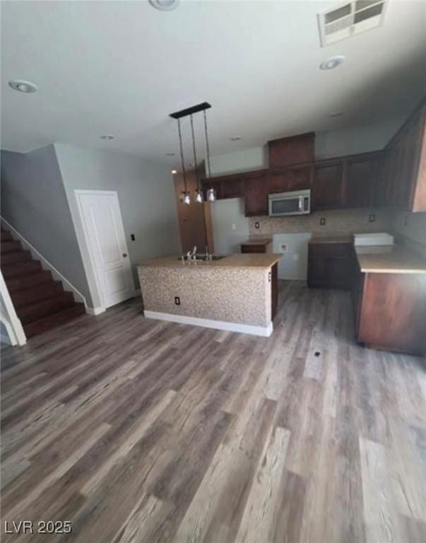 7349 Dolphine Crest Ave, Las Vegas, NV 89129 - kitchen featuring stainless steel microwave, wood finished floors, a center island, and pendant lighting