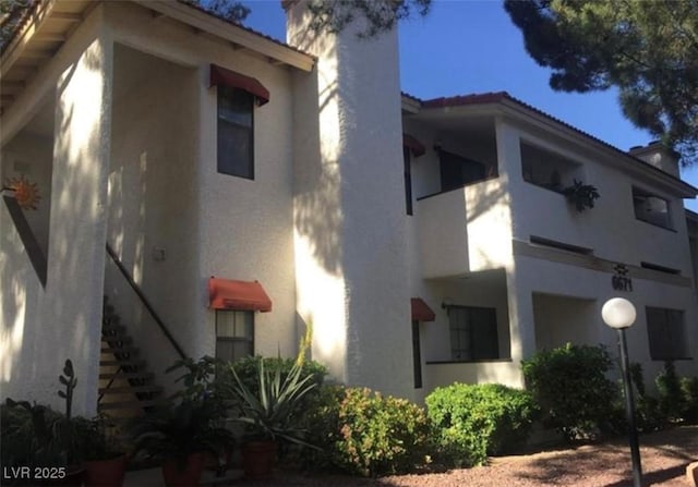 6671 W Tropicana Ave Unit 103, Las Vegas, NV 89103 - view of property exterior featuring a chimney, stucco siding, and stairs