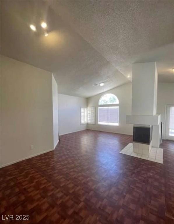 9820 Cross Creek Way, Las Vegas, NV 89117 - unfurnished living room featuring lofted ceiling, healthy amount of natural light, a textured ceiling, and a tiled fireplace