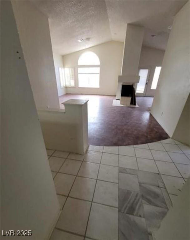9820 Cross Creek Way, Las Vegas, NV 89117 - unfurnished living room with vaulted ceiling, light tile patterned floors, and a textured ceiling