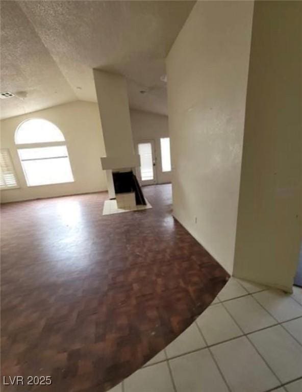 9820 Cross Creek Way, Las Vegas, NV 89117 - unfurnished living room featuring vaulted ceiling, a textured ceiling, and a fireplace
