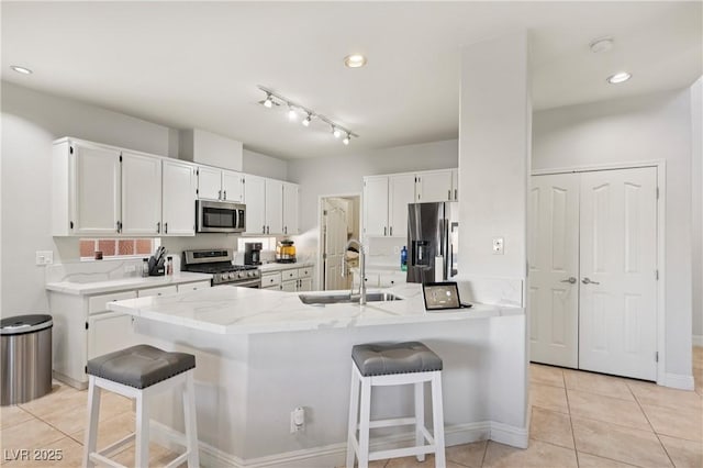 217 Turkey Creek Way, Henderson, NV 89074 - kitchen with stainless steel appliances, light tile patterned floors, white cabinetry, a breakfast bar, and recessed lighting