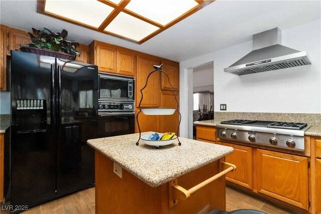 9109 Anchor Cove Ct, Las Vegas, NV 89117 - kitchen with black appliances, wall chimney range hood, brown cabinetry, light wood-type flooring, and a kitchen island