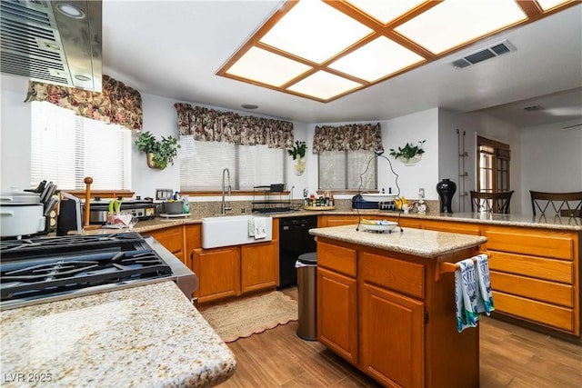 9109 Anchor Cove Ct, Las Vegas, NV 89117 - kitchen with black dishwasher, light wood finished floors, a kitchen island, and stainless steel gas range