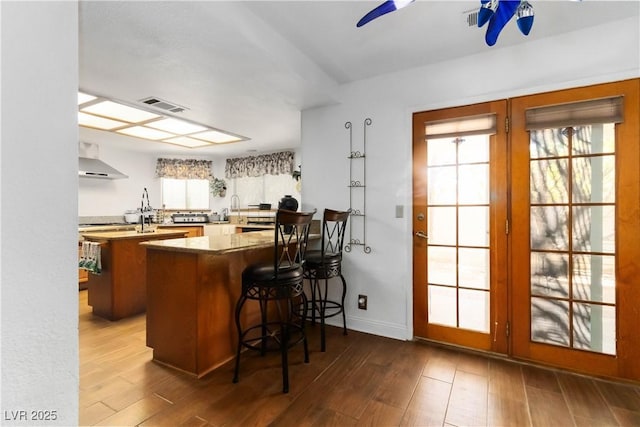 9109 Anchor Cove Ct, Las Vegas, NV 89117 - kitchen with a peninsula, wood finished floors, healthy amount of natural light, and exhaust hood