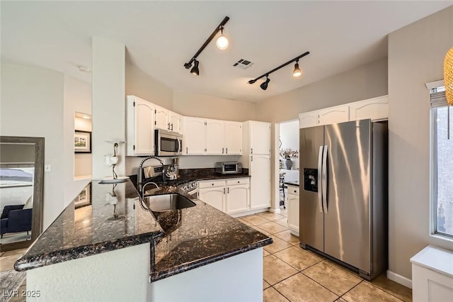 2535 Cortina Ave, Henderson, NV 89074 - kitchen featuring stainless steel appliances, a peninsula, dark stone counters, white cabinetry, and light tile patterned flooring