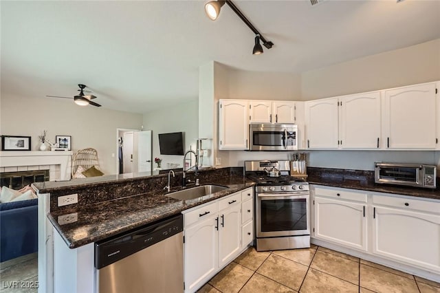 2535 Cortina Ave, Henderson, NV 89074 - kitchen featuring appliances with stainless steel finishes, a peninsula, white cabinets, open floor plan, and dark stone countertops