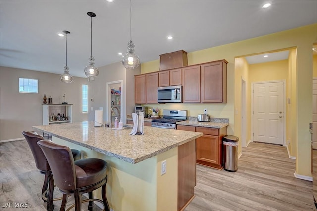 6322 Highledge St, North Las Vegas, NV 89081 - kitchen with appliances with stainless steel finishes, light wood-style floors, a kitchen breakfast bar, light stone countertops, and decorative light fixtures