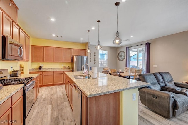6322 Highledge St, North Las Vegas, NV 89081 - kitchen featuring stainless steel appliances, open floor plan, light wood-style floors, a kitchen island with sink, and light stone counters