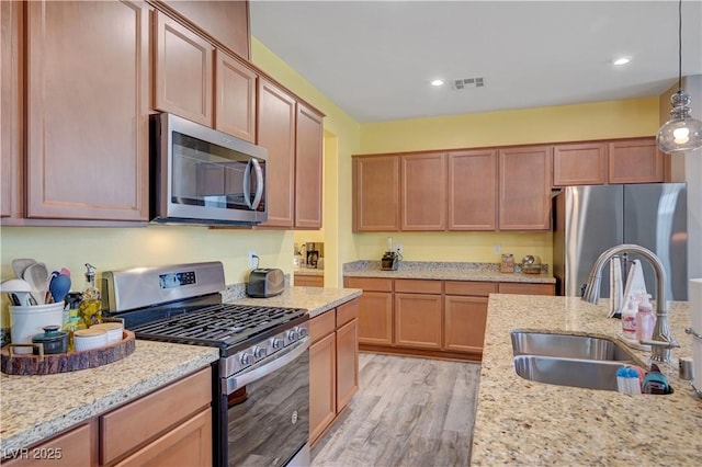 6322 Highledge St, North Las Vegas, NV 89081 - kitchen with stainless steel appliances, light wood-style floors, light stone countertops, hanging light fixtures, and recessed lighting