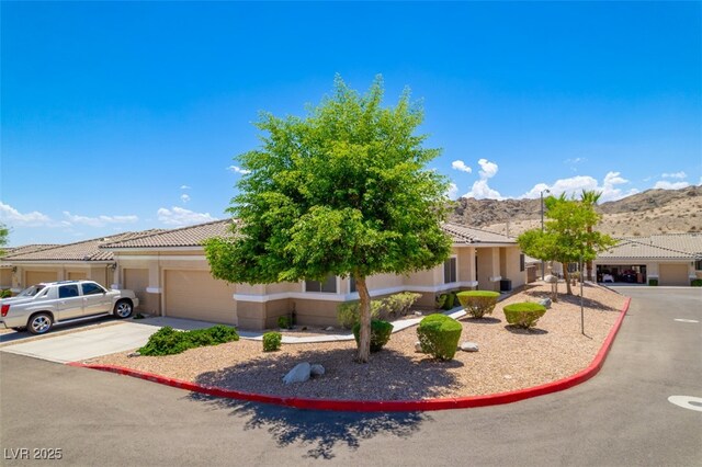 3251 Pheasant Hills Way, Laughlin, NV 89029 - obstructed view of property with a garage, a mountain view, concrete driveway, stucco siding, and a tile roof