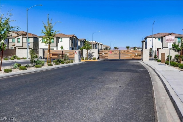 6831 Crimson Shadow St, North Las Vegas, NV 89086 - view of asphalt street featuring a residential view, a gate, street lighting, and curbs