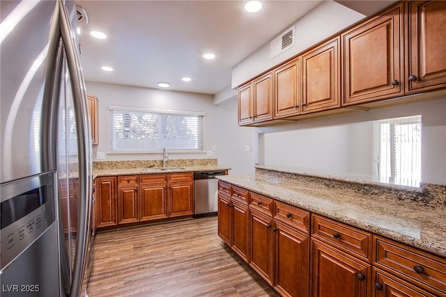 4307 Lucas Ave, Las Vegas, NV 89120 - kitchen with stainless steel appliances, brown cabinets, light stone countertops, light wood finished floors, and recessed lighting