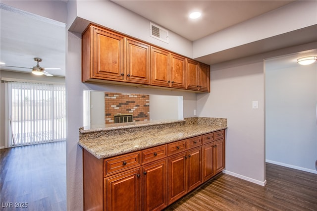 4307 Lucas Ave, Las Vegas, NV 89120 - kitchen with dark wood-style floors, brown cabinets, light stone counters, ceiling fan, and a peninsula