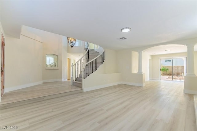 1846 Autumn Gold Ave, Las Vegas, NV 89123 - unfurnished living room with decorative columns, stairway, light wood finished floors, arched walkways, and a chandelier