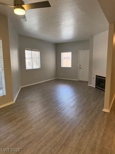 5250 S Rainbow Blvd Unit 1155, Las Vegas, NV 89118 - unfurnished living room featuring dark wood-style floors, a textured ceiling, a tiled fireplace, and ceiling fan