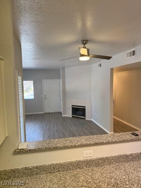 5250 S Rainbow Blvd Unit 1155, Las Vegas, NV 89118 - unfurnished living room featuring wood finished floors, a ceiling fan, a tile fireplace, and a textured ceiling