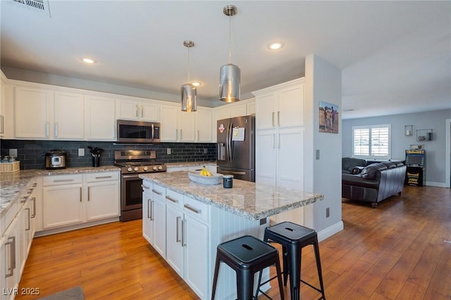 212 Stour Ln, Las Vegas, NV 89144 - kitchen featuring stainless steel appliances, white cabinets, a kitchen breakfast bar, decorative backsplash, and recessed lighting