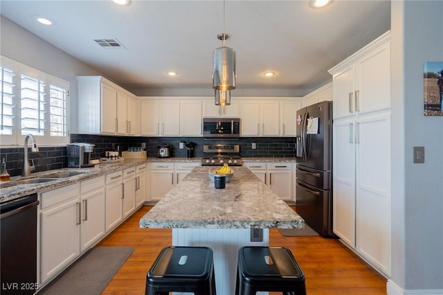 212 Stour Ln, Las Vegas, NV 89144 - kitchen featuring appliances with stainless steel finishes, a center island, white cabinets, backsplash, and recessed lighting