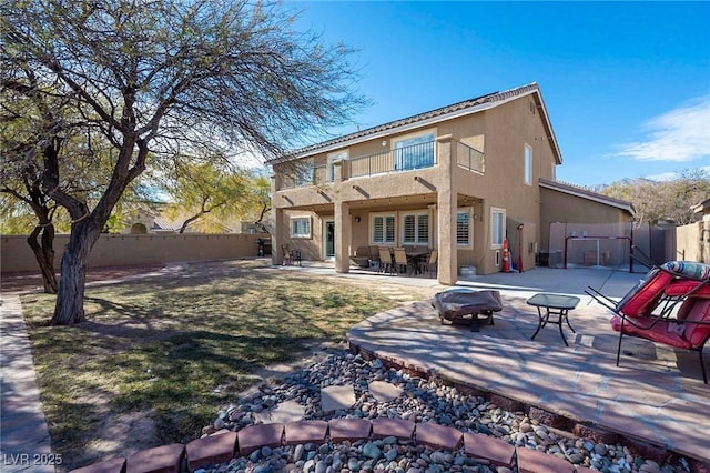 212 Stour Ln, Las Vegas, NV 89144 - back of house featuring a balcony, a fenced backyard, stucco siding, and an outdoor fire pit