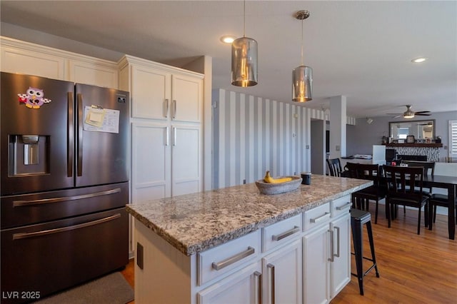 212 Stour Ln, Las Vegas, NV 89144 - kitchen with stainless steel fridge with ice dispenser, ceiling fan, white cabinetry, light wood-style floors, and light stone countertops