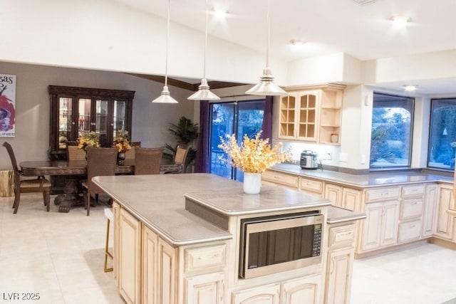 3430 Tanto Cir, Las Vegas, NV 89121 - kitchen with stainless steel microwave, cream cabinets, a center island, vaulted ceiling, and decorative light fixtures