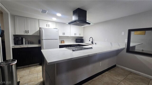 2941 Country Manor Ln Unit 27, Las Vegas, NV 89115 - kitchen with island exhaust hood, black appliances, a peninsula, light stone counters, and white cabinetry