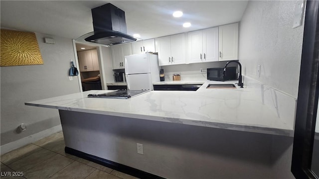 2941 Country Manor Ln Unit 27, Las Vegas, NV 89115 - kitchen with freestanding refrigerator, island range hood, a peninsula, black microwave, and light stone counters