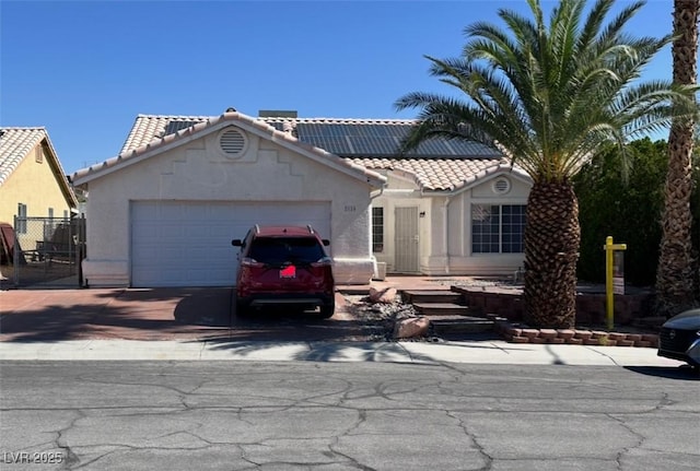 2124 Cabrini Ct, North Las Vegas, NV 89032 - view of front facade featuring concrete driveway, a tile roof, an attached garage, stucco siding, and roof mounted solar panels