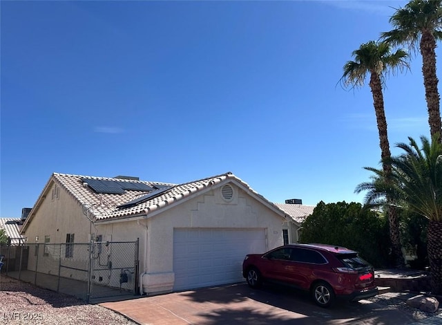 2124 Cabrini Ct, North Las Vegas, NV 89032 - view of side of property featuring an attached garage, a gate, roof mounted solar panels, a tiled roof, and stucco siding