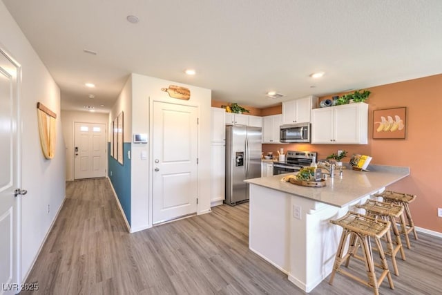 10988 Rollingford Ave Lot 10, Las Vegas, NV 89166 - kitchen featuring appliances with stainless steel finishes, a peninsula, white cabinetry, light wood-type flooring, and recessed lighting