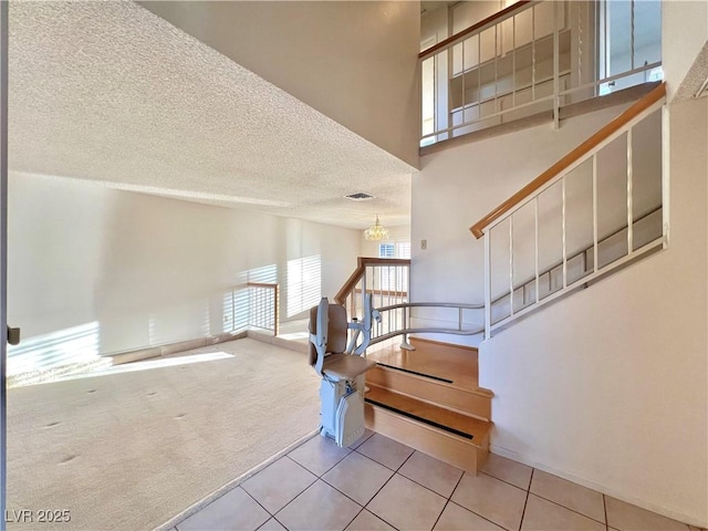 304 Broxton Ln, Las Vegas, NV 89107 - stairs featuring tile patterned floors, carpet floors, a textured ceiling, a chandelier, and a high ceiling