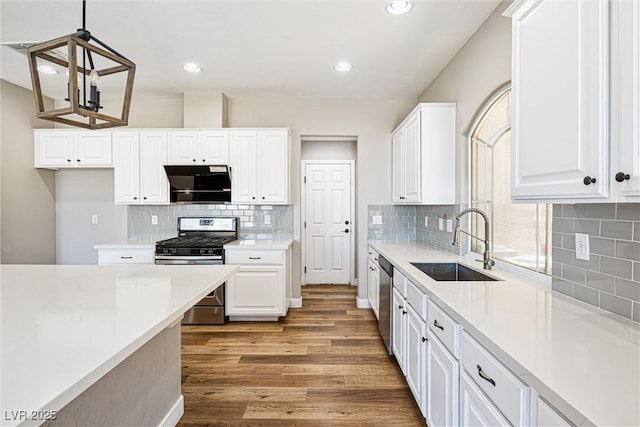 9432 Logan Ridge Ct, Las Vegas, NV 89139 - kitchen with stainless steel appliances, light countertops, range hood, light wood finished floors, and recessed lighting