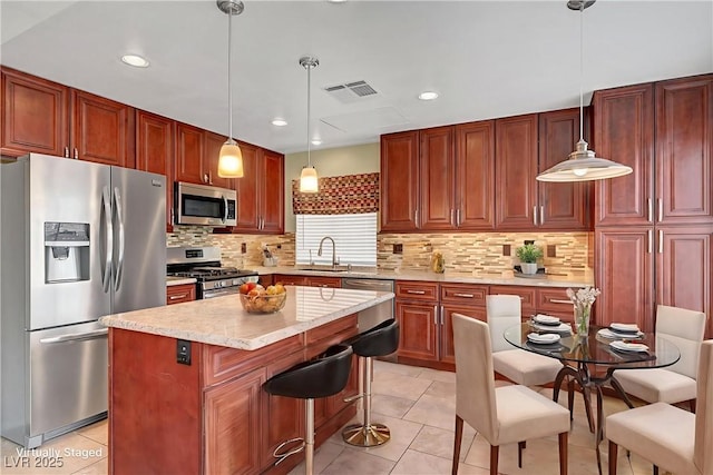 1424 Colt Dr, Henderson, NV 89002 - kitchen featuring stainless steel appliances, light tile patterned floors, a center island, a kitchen breakfast bar, and tasteful backsplash