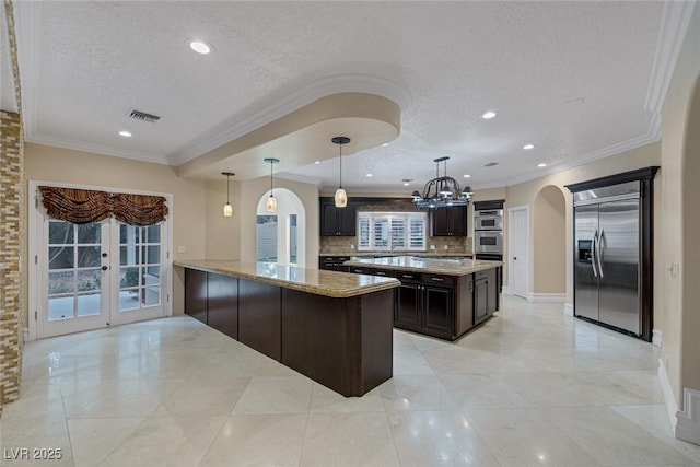 81 Quail Run Rd, Henderson, NV 89014 - kitchen featuring appliances with stainless steel finishes, a textured ceiling, arched walkways, tasteful backsplash, and light stone counters