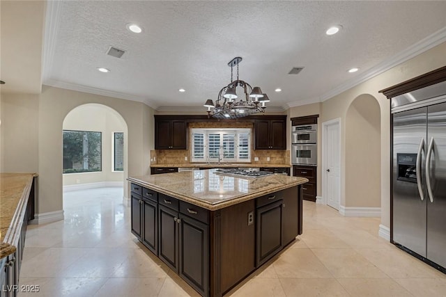 81 Quail Run Rd, Henderson, NV 89014 - kitchen with arched walkways, stainless steel appliances, decorative backsplash, a kitchen island, and recessed lighting