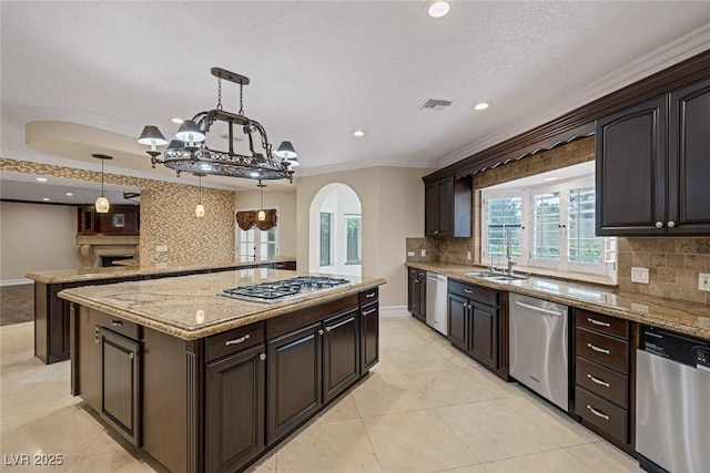 81 Quail Run Rd, Henderson, NV 89014 - kitchen with stainless steel appliances, arched walkways, a kitchen island, ornamental molding, and a chandelier