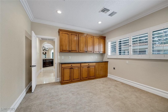81 Quail Run Rd, Henderson, NV 89014 - kitchen with brown cabinetry, ornamental molding, light carpet, healthy amount of natural light, and arched walkways