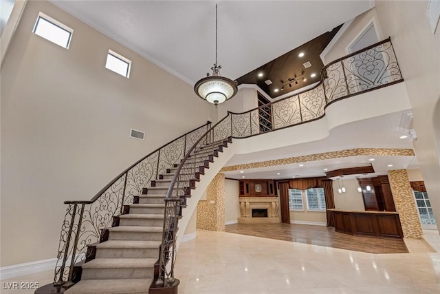 81 Quail Run Rd, Henderson, NV 89014 - staircase featuring a towering ceiling, healthy amount of natural light, a fireplace, marble finish floors, and crown molding