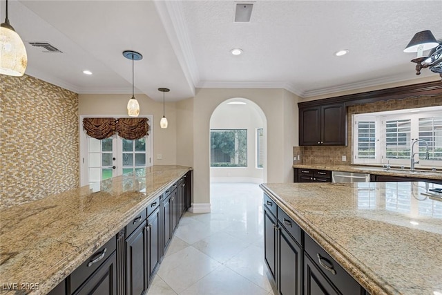 81 Quail Run Rd, Henderson, NV 89014 - kitchen featuring arched walkways, backsplash, dishwasher, decorative light fixtures, and ornamental molding