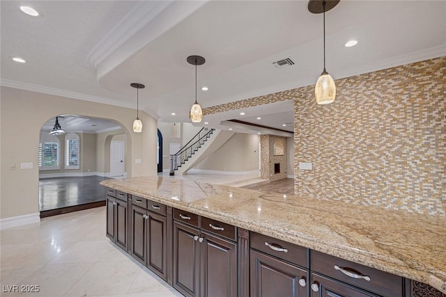 81 Quail Run Rd, Henderson, NV 89014 - kitchen with arched walkways, open floor plan, ornamental molding, hanging light fixtures, and dark brown cabinets