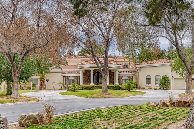 81 Quail Run Rd, Henderson, NV 89014 - mediterranean / spanish home featuring curved driveway, stucco siding, a tile roof, and stone siding