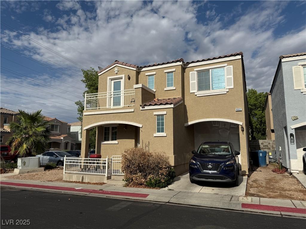 10322 Tranquil Breeze St, Las Vegas, NV 89183 - view of front of property featuring a balcony, a tiled roof, stucco siding, an attached garage, and concrete driveway
