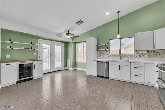 658 Turtleback Dr, North Las Vegas, NV 89031 - kitchen with beverage cooler, open shelves, dishwasher, vaulted ceiling, and backsplash