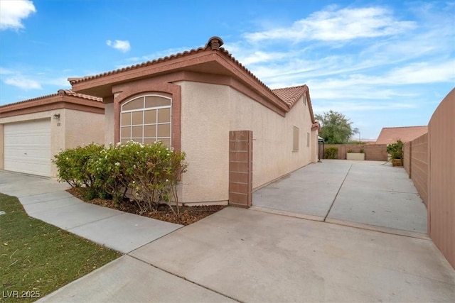 658 Turtleback Dr, North Las Vegas, NV 89031 - view of home's exterior with stucco siding, a tile roof, an attached garage, and a fenced backyard