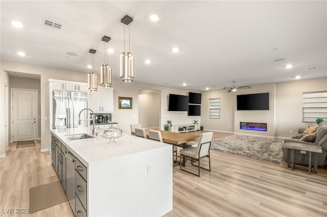 186 Vista Balla Ave, Las Vegas, NV 89138 - kitchen with stainless steel refrigerator with ice dispenser, white cabinets, light wood-style floors, ceiling fan, and an island with sink