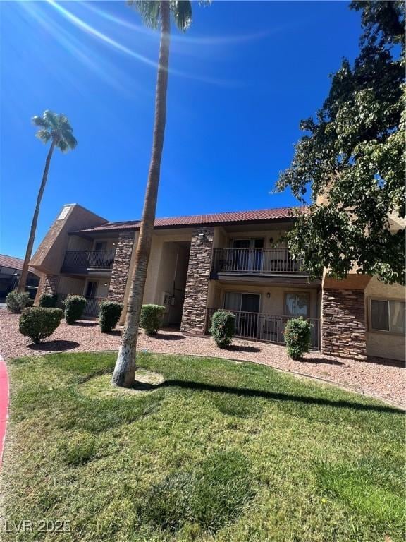 5350 River Glen Dr Unit 298, Las Vegas, NV 89103 - view of front of house featuring stone siding, a tile roof, a front yard, and stucco siding