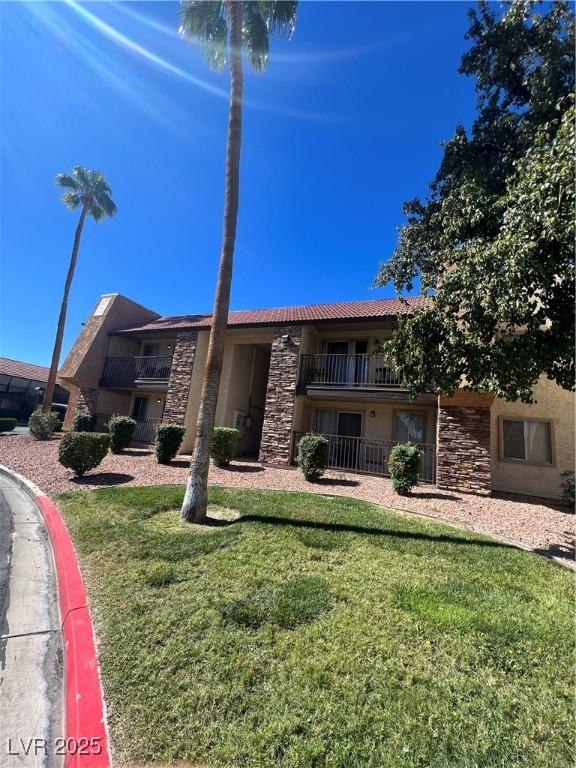 5350 River Glen Dr Unit 298, Las Vegas, NV 89103 - view of front facade with stone siding, a front lawn, a tile roof, and stucco siding