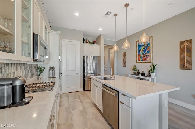 9940 Heather Moore Ave, Las Vegas, NV 89166 - kitchen with appliances with stainless steel finishes, light countertops, white cabinets, hanging light fixtures, and an island with sink